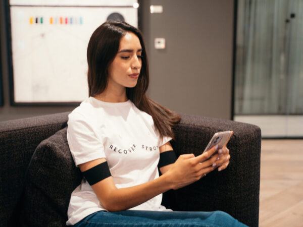 Woman wearing Recovery Strong shirt and She Rex band